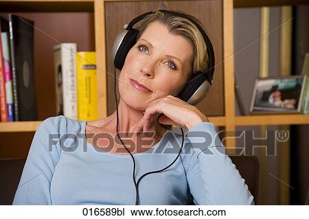 Stock Image - portrait of mature woman listening to music with headphones. Fotosearch
