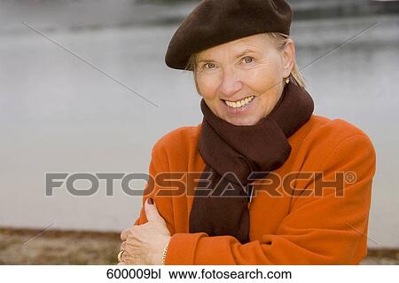 Portrait of mature woman wearing brown beret standing at lake in park