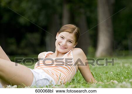 portrait of smiling young woman lying on lawn in park View Large Photo Image Stock Image - portrait of smiling young woman lying on lawn in park. Fotosearch