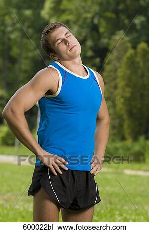 Stock Image - portrait of young man doing exercises in park. Fotosearch