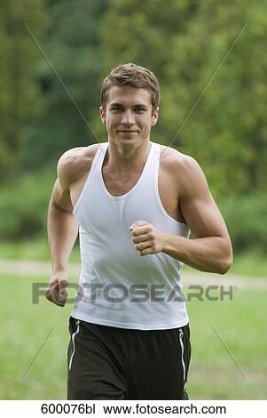 portrait of young man jogging through park View Large Photo Image Stock Image - portrait of young man jogging through park. Fotosearch