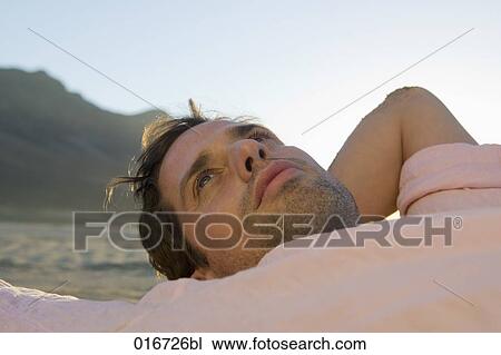 portrait of young man lying on beach looking worried View Large Photo Image Stock Image - portrait of young man lying on beach looking worried. Fotosearch