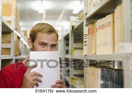 portrait of young student hiding mischiefly behind documents in school library View Large Photo Image Stock Image - portrait of young student hiding mischiefly behind documents in school library. Fotosearch