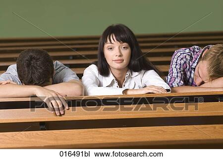 Stock Image - portrait of young student in lecture hall while all others are sleeping. Fotosearch