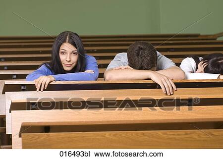Stock Image - portrait of young student in lecture hall while all others are sleeping. Fotosearch