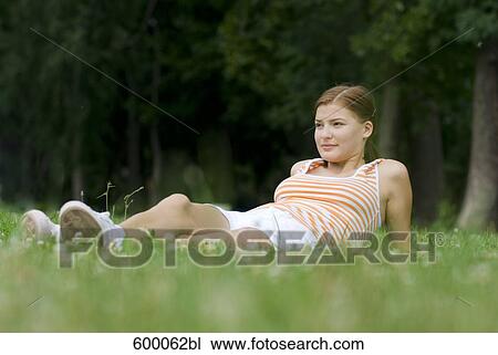 portrait of young woman lying on lawn in park View Large Photo Image Stock Image - portrait of young woman lying on lawn in park. Fotosearch