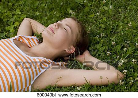 portrait of young woman relaxing on lawn in park View Large Photo Image Stock Image - portrait of young woman relaxing on lawn in park. Fotosearch