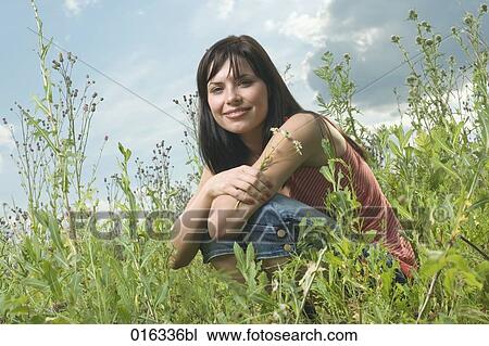 portrait of young woman sitting in meadow holding flowers View Large Photo Image Stock Image - portrait of young woman sitting in meadow holding flowers. Fotosearch