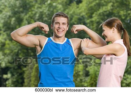 portrait of young woman touching bicep of boyfriend View Large Photo Image Stock Image - portrait of young woman touching bicep of boyfriend. Fotosearch