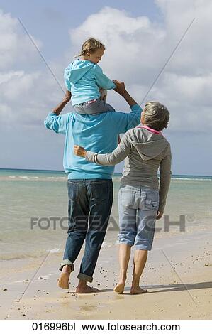rear view of grandparents walking along beach with grandfather carrying young girl piggback View Large Photo Image Stock Image - rear view of grandparents walking along beach with grandfather carrying young girl piggback. Fotosearch