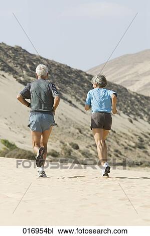 rear view of mature couple jogging on sandy beach View Large Photo Image Stock Image - rear view of mature couple jogging on sandy beach. Fotosearch