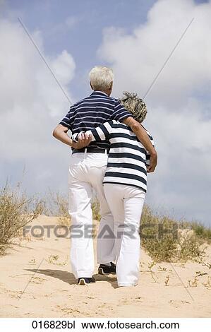 rear view of mature couple walking on beach View Large Photo Image Stock Image - rear view of mature couple walking on beach. Fotosearch