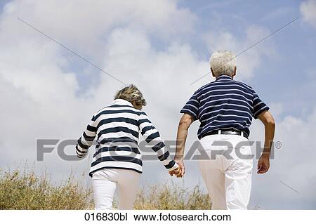 rear view of mature couple walking on beach View Large Photo Image Stock Image - rear view of mature couple walking on beach. Fotosearch