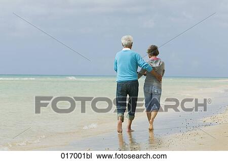 rear view of mature couple walking along beach View Large Photo Image Stock Image - rear view of mature couple walking along beach. Fotosearch