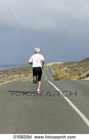 rear view of mature man jogging along empty road View Large Photo Image Stock Image - rear view of mature man jogging along empty road. Fotosearch