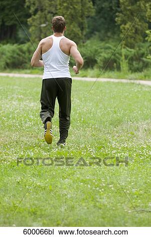 rear view of young man jogging through park View Large Photo Image Stock Image - rear view of young man jogging through park. Fotosearch
