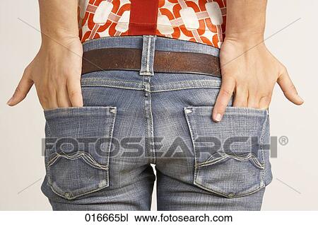Stock Image - rear view of young woman putting hands in pockets of her jeans. Fotosearch