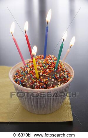 Stock Image - still life of muffin decorated with six burning candles. Fotosearch