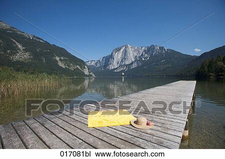 still life of straw hat and towel on pier in alpine landscape View Large Photo Image Stock Image - still life of straw hat and towel on pier in alpine landscape. Fotosearch