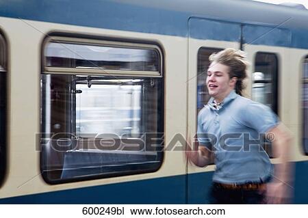 Stock Image - teenage boy running to catch underground train. Fotosearch