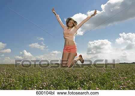 Stock Image - teenage girl jumping in summer meadow. Fotosearch