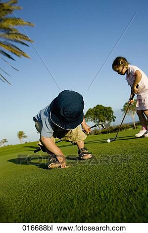 two siblings playing golf little boy looking for ball View Large Photo Image Stock Image - two siblings playing golf little boy looking for ball. Fotosearch