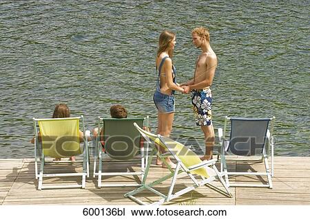 young couple holding hands amongst sunloungers on pier View Large Photo Image Stock Image - young couple holding hands amongst sunloungers on pier. Fotosearch