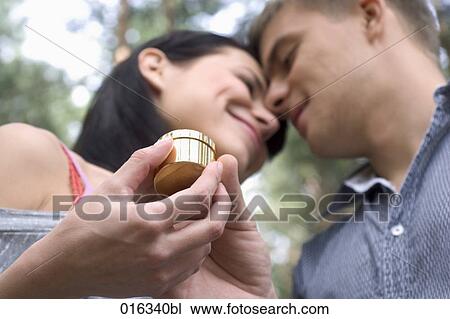 young couple looking at each other woman receiving present in golden box View Large Photo Image Stock Image - young couple looking at each other woman receiving present in golden box. Fotosearch