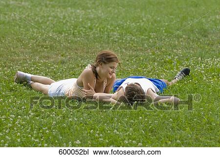 young couple lying on lawn in park flirting with each other View Large Photo Image Stock Image - young couple lying on lawn in park flirting with each other. Fotosearch