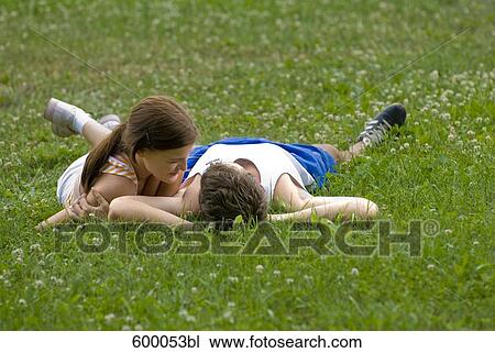 young couple lying on lawn in park flirting with each other View Large Photo Image Stock Image - young couple lying on lawn in park flirting with each other. Fotosearch