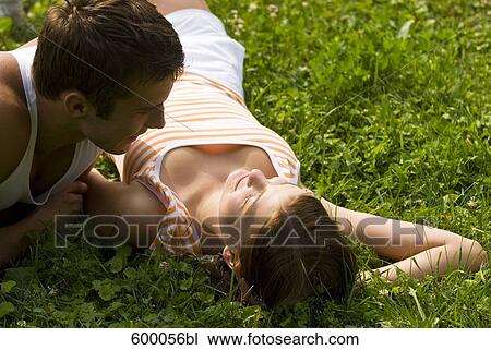 young couple lying on lawn in park flirting with each other View Large Photo Image Stock Image - young couple lying on lawn in park flirting with each other. Fotosearch