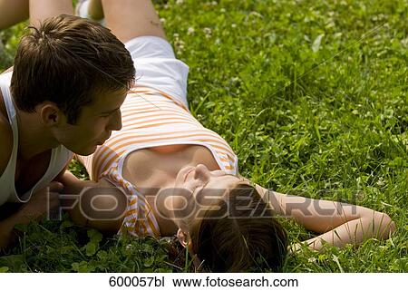 young couple lying on lawn in park flirting with each other View Large Photo Image Stock Image - young couple lying on lawn in park flirting with each other. Fotosearch