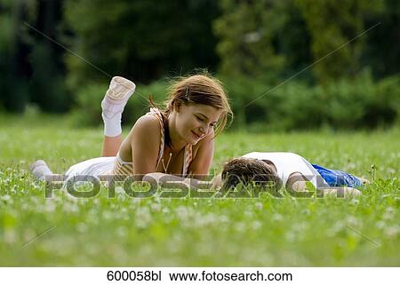 young couple lying on lawn in park flirting with each other View Large Photo Image Stock Image - young couple lying on lawn in park flirting with each other. Fotosearch