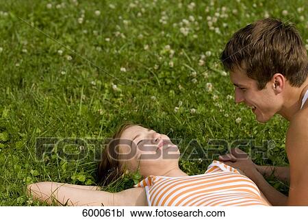 young couple lying on lawn in park flirting with each other View Large Photo Image Stock Image - young couple lying on lawn in park flirting with each other. Fotosearch