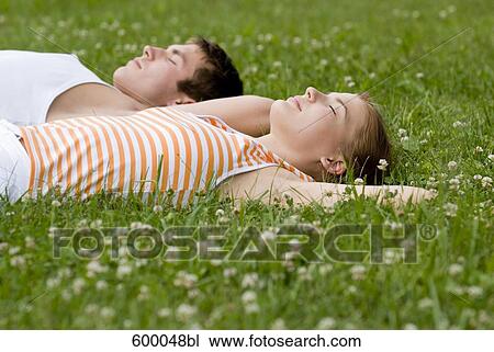 young couple relaxing on lawn in park View Large Photo Image Stock Image - young couple relaxing on lawn in park. Fotosearch