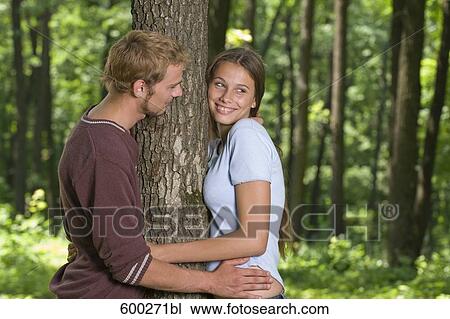 young couple standing at tree in forest View Large Photo Image Stock Image - young couple standing at tree in forest. Fotosearch