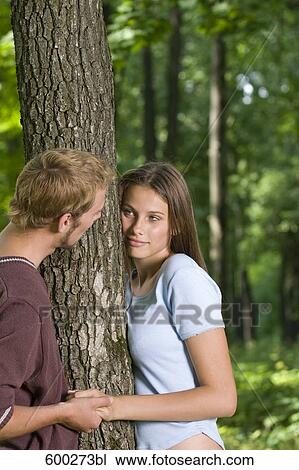young couple standing at tree tenderly looking at each other View Large Photo Image Stock Image - young couple standing at tree tenderly looking at each other. Fotosearch