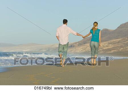 young couple walking along beach together View Large Photo Image Stock Image - young couple walking along beach together. Fotosearch