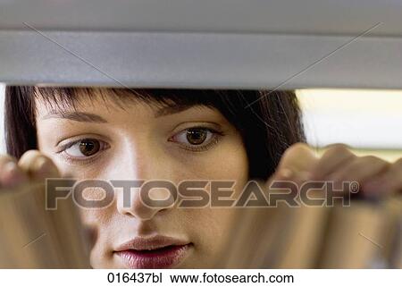 Stock Image - young female student looking for books in school library. Fotosearch