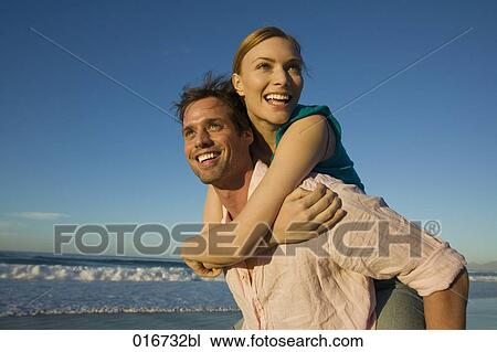 young man giving woman piggyback ride on beach View Large Photo Image Stock Image - young man giving woman piggyback ride on beach. Fotosearch