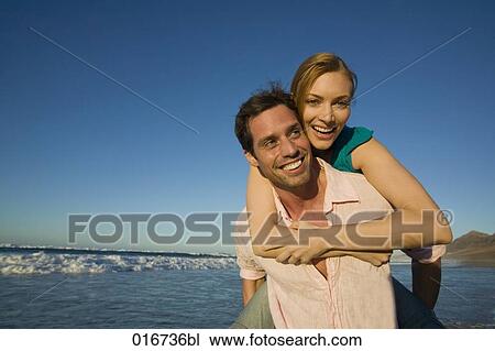 young man giving woman piggyback ride on beach View Large Photo Image Stock Image - young man giving woman piggyback ride on beach. Fotosearch
