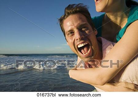 young man giving woman piggyback ride on beach View Large Photo Image Stock Image - young man giving woman piggyback ride on beach. Fotosearch
