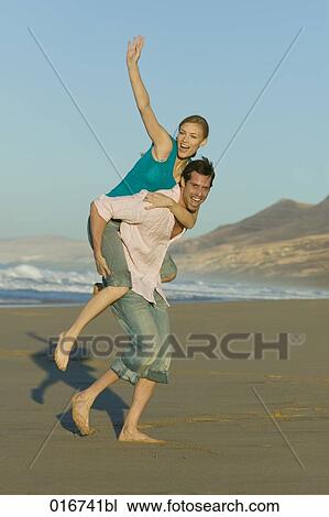 young man giving woman piggyback ride on beach View Large Photo Image Stock Image - young man giving woman piggyback ride on beach. Fotosearch