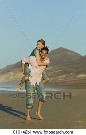 young man giving woman piggyback ride on beach View Large Photo Image Stock Image - young man giving woman piggyback ride on beach. Fotosearch