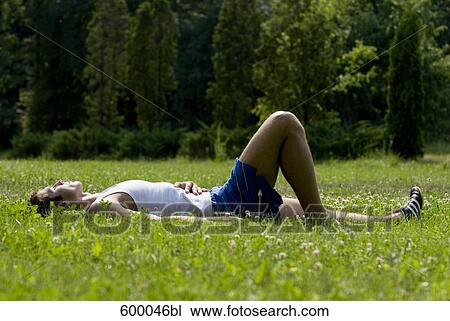 young man in sportswear relaxing on lawn in park View Large Photo Image Stock Image - young man in sportswear relaxing on lawn in park. Fotosearch