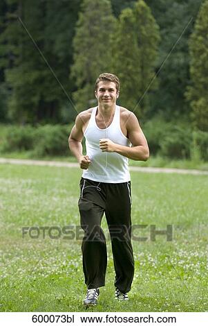 young man jogging through park and listening to music View Large Photo Image Stock Image - young man jogging through park and listening to music. Fotosearch