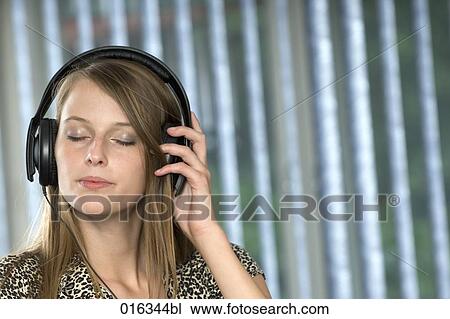 young woman with eyes closed wearing earphones and listening to music View Large Photo Image Stock Image - young woman with eyes closed wearing earphones and listening to music. Fotosearch