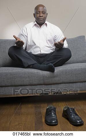 black businessman sitting on sofa meditating View Large Photo Image Stock Image - black businessman sitting on sofa meditating. Fotosearch