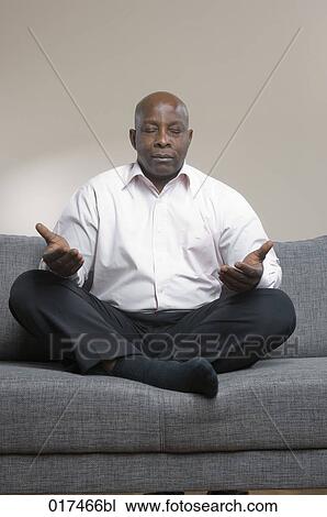 black businessman sitting on sofa meditating View Large Photo Image Stock Image - black businessman sitting on sofa meditating. Fotosearch