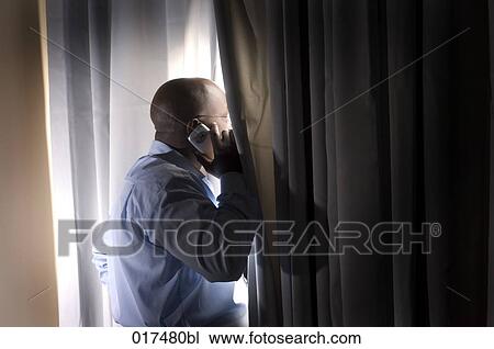 black businessman standing at window curtain talking on mobile phone View Large Photo Image Stock Image - black businessman standing at window curtain talking on mobile phone. Fotosearch